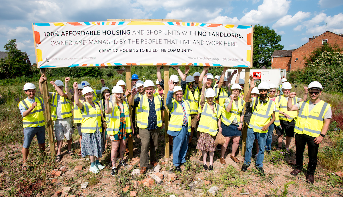 Members of SCD and local dignitaries holding a banner saying "100% affordable housing and shop units with no landlords, owned and managed by the people that live and work here."