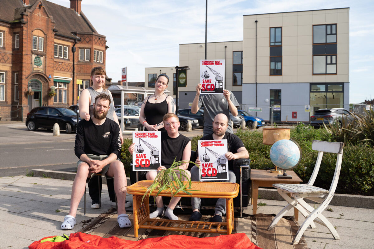 Members of SCD posing in front of the much delayed building with furniture, ready to move in